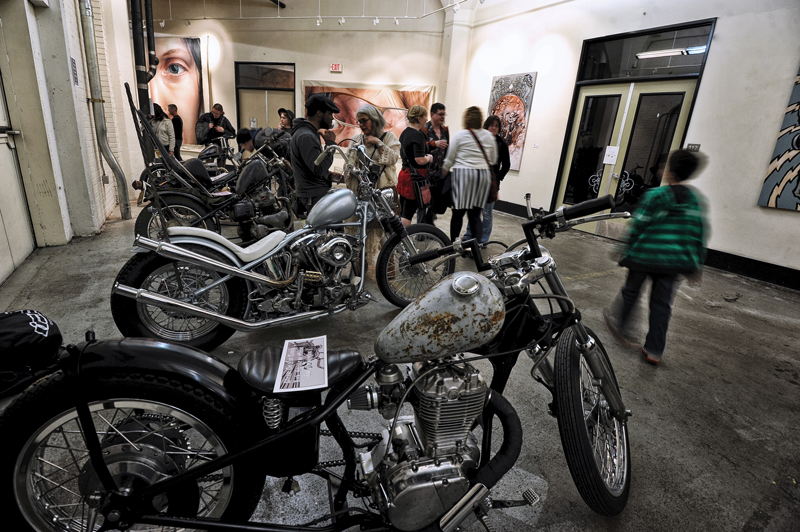 A view of the exhibit with Tony Morgan’s motorcycles. In the background are Coatney’s paintings and one of Morgan’s paintings to the right of the frame.
