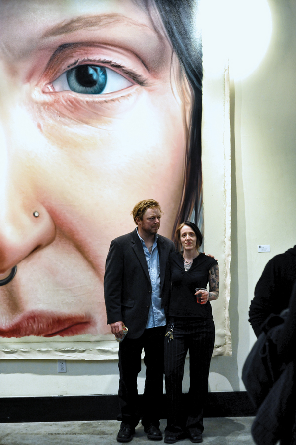 Left to right: Painter Jason Coatney with artist Emily Kosta in front of Coatney’s painting of Kosta.
